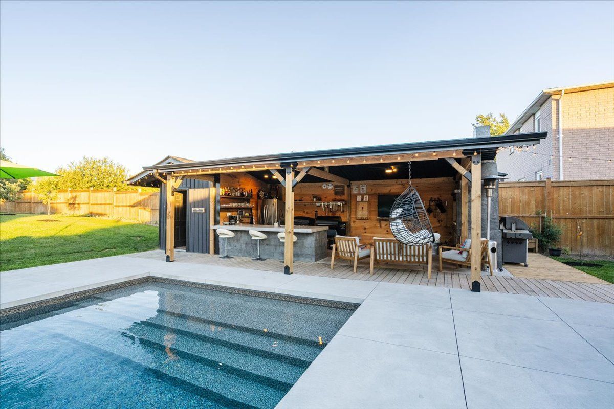 There is a large swimming pool in the backyard of a house.