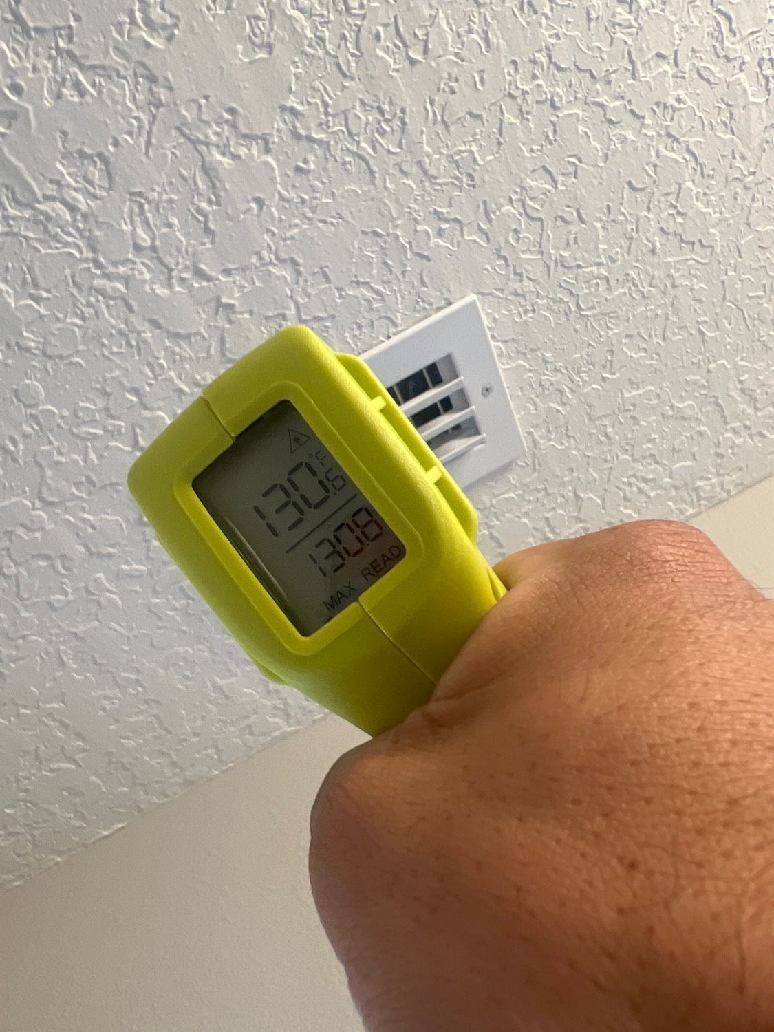 A person is holding a yellow thermometer in their hand.