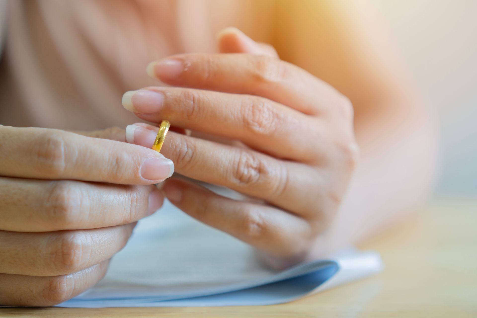 Hands placing a gold ring on a finger over a notebook, close-up.