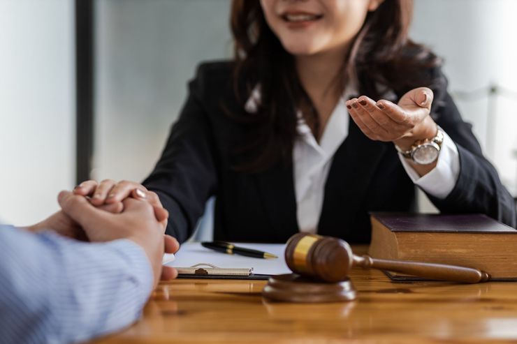 Lawyer shaking hands with client across a desk, with a gavel and papers in the foreground