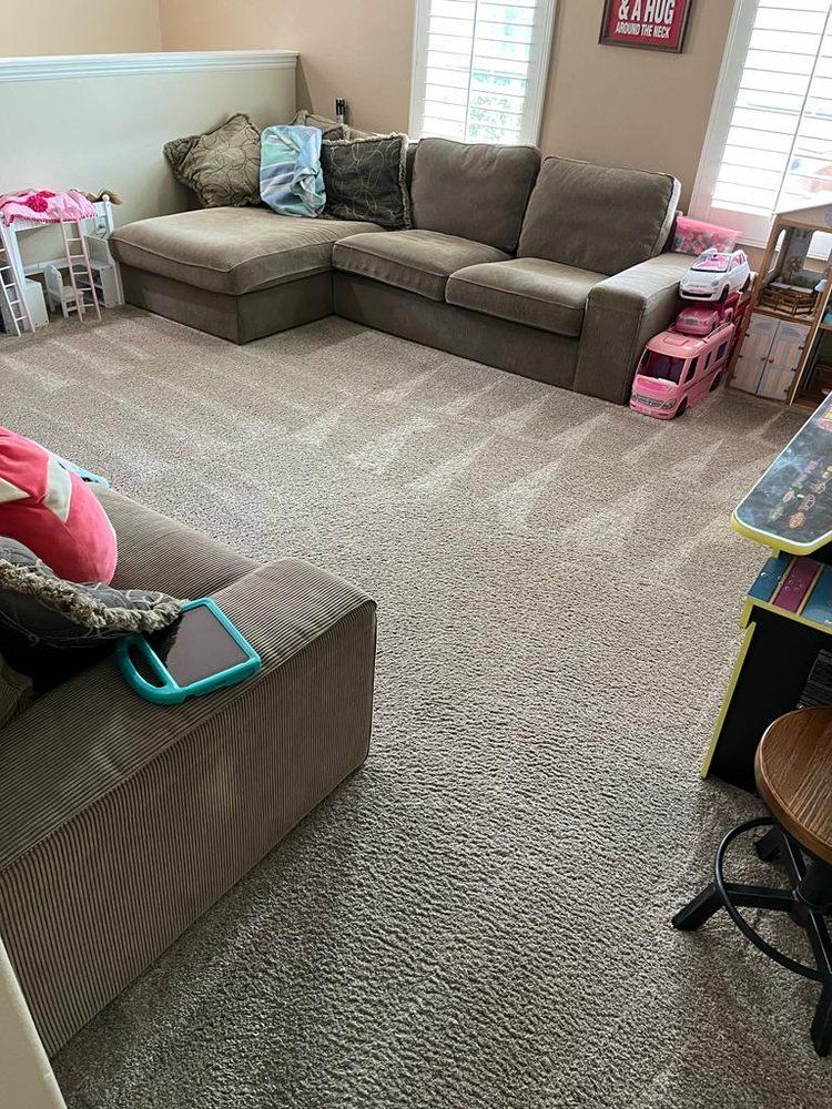 Image of a home living room with a tan sofa and gray carpet
