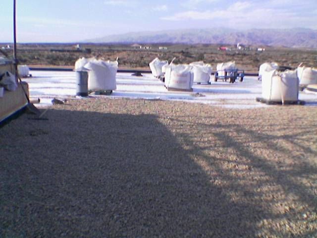 Azotea con rejillas de ventilación cilíndricas blancas y grava bajo un cielo despejado, con vistas a un paisaje lejano.
