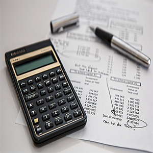 Calculator, pen, and financial documents on a white surface; for calculations.