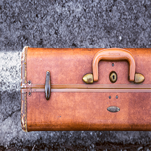 Brown vintage suitcase on a gray, cracked surface, with a white line.