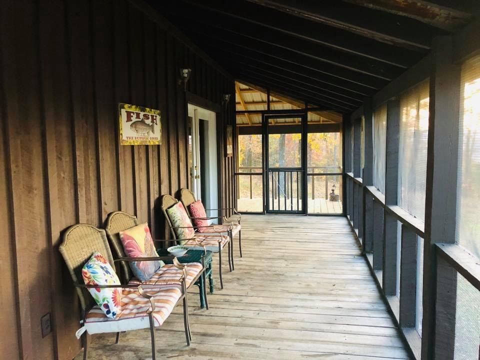 Covered porch with chairs. Wooden building with screened door.