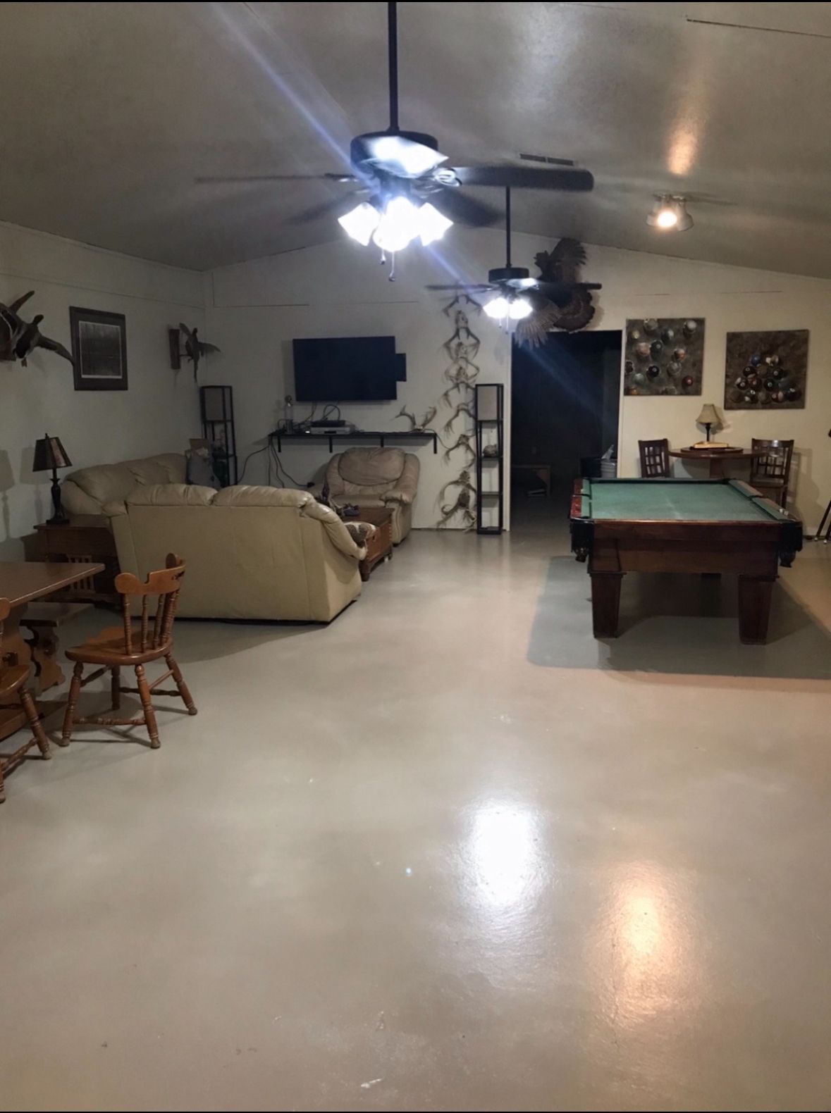 Spacious living room with a pool table, beige sofa, ceiling fan, and wall-mounted TV.