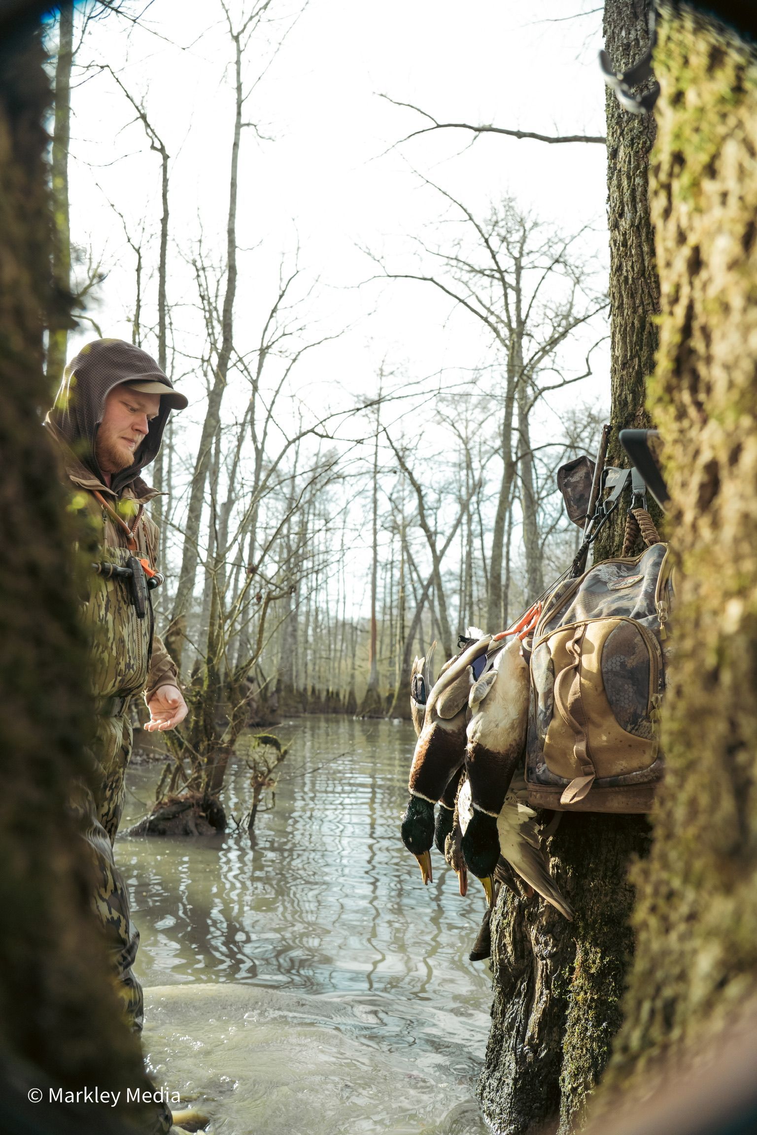 Soldiers wading through a flooded forest, carrying gear and moving along a tree line.