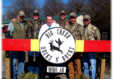 Six people pose behind a Big Creek Ducks N Geese sign at Moro, AR.