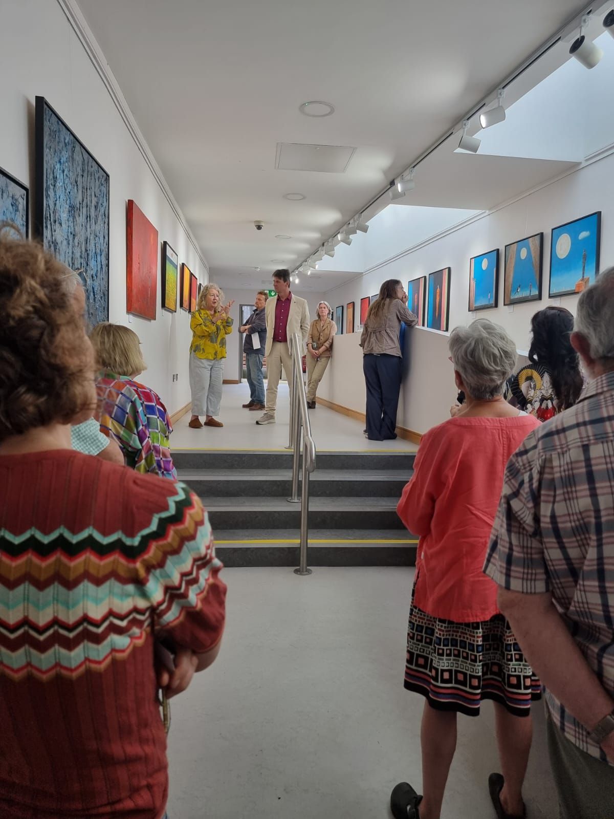 The artist stands with speaker Patricia Moriarty as visitors explore his solo exhibition at Scariff Library Gallery
