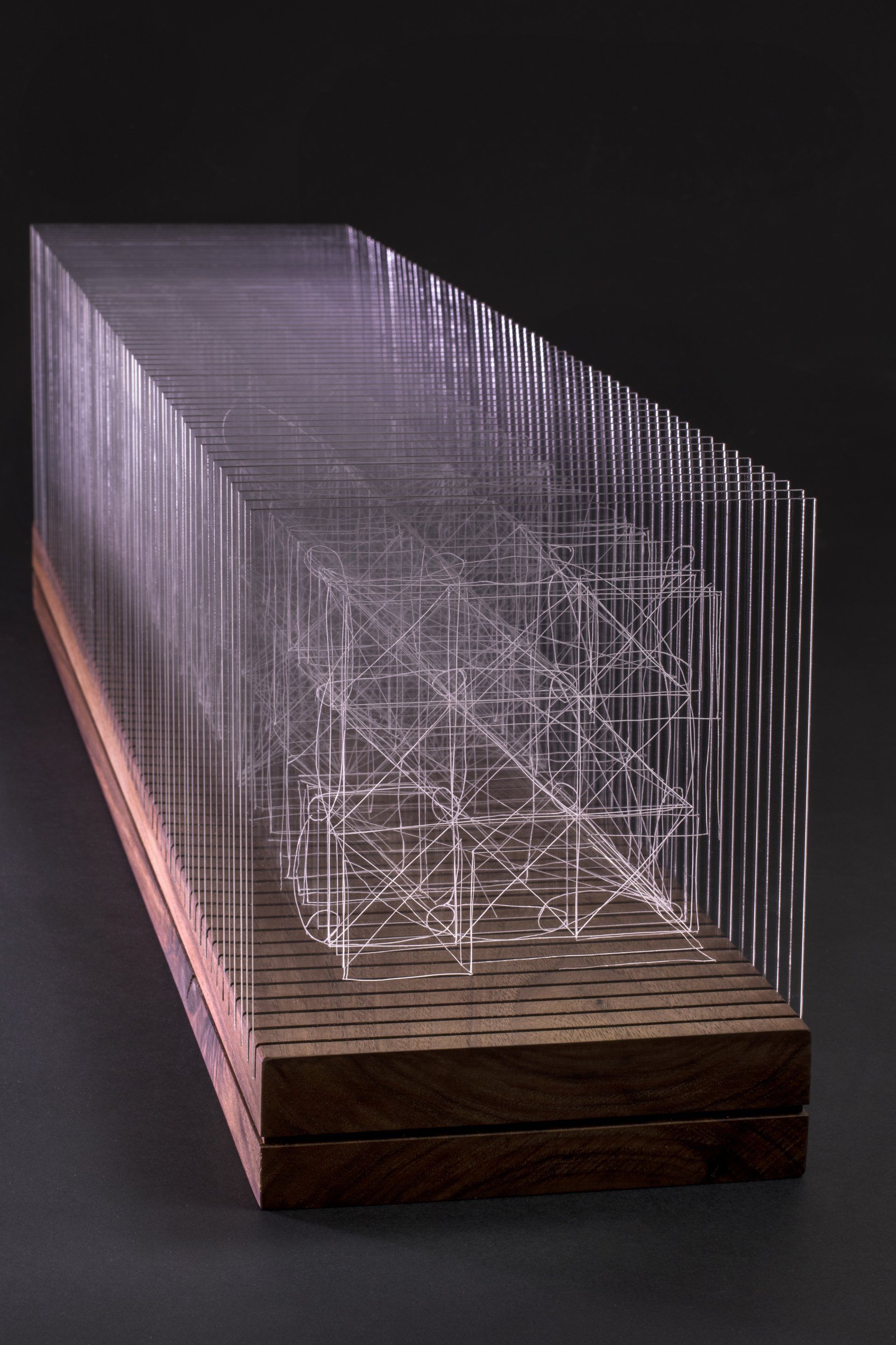 Side view of Connection sculpture showing engraved acrylic panels mounted in an oiled walnut base