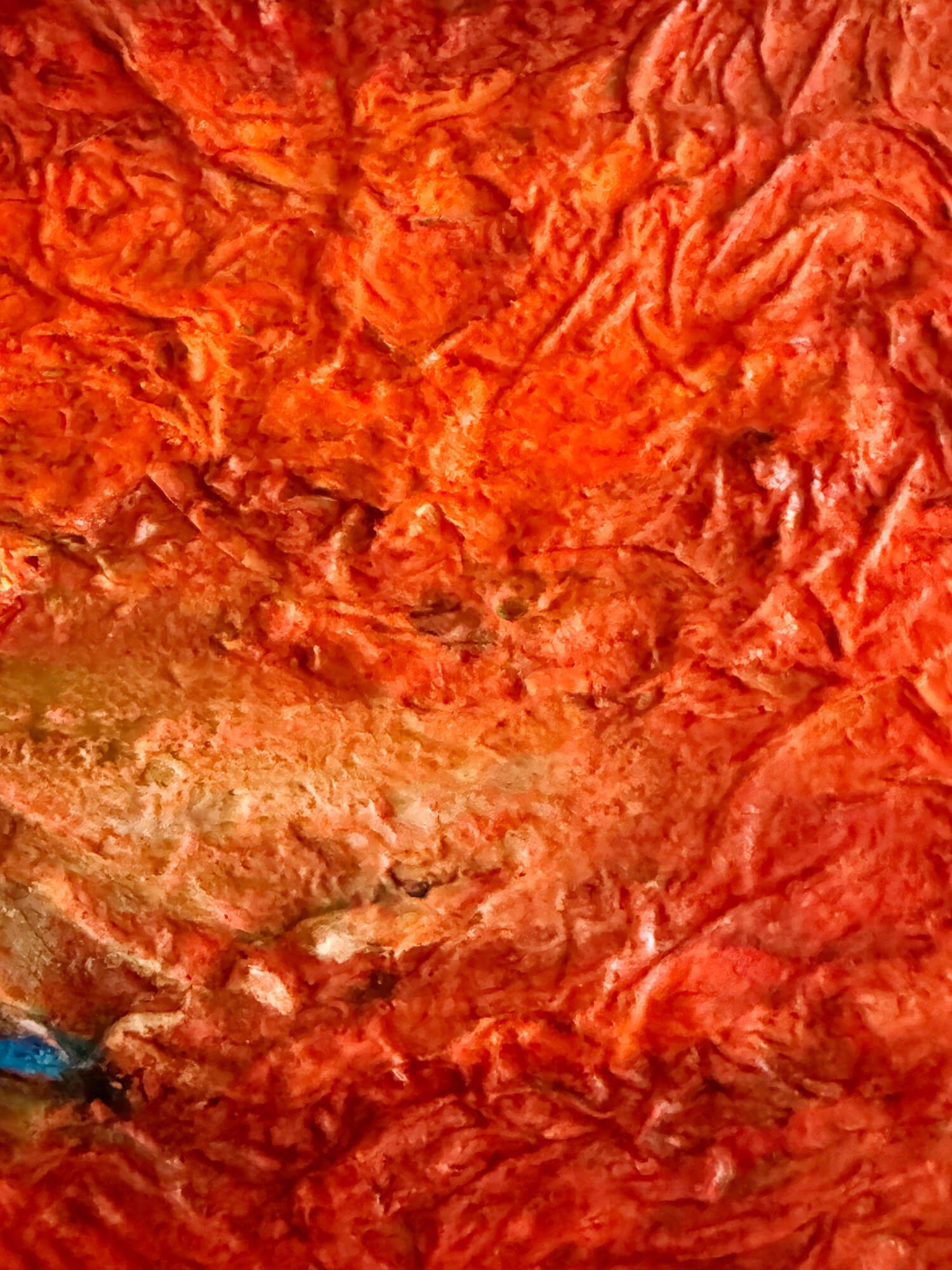 Close-up of the layered red and ochre surface and dark blue detail in The Last Drop