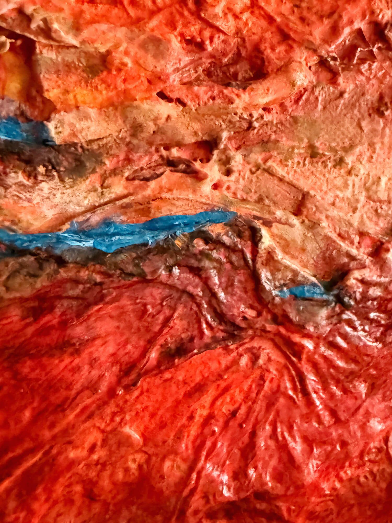 Close-up of rock-like red and pink forms crossed by a narrow blue passage in The Last Drop