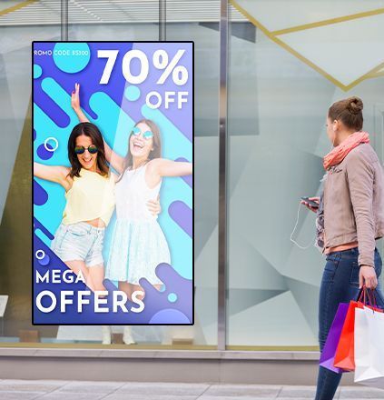Een vrouw loopt langs een winkelraam met een advertentie voor 70% korting. Op de etalage zijn twee vrouwen met zonnebrillen te zien.