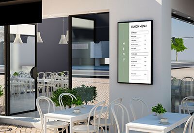 Terras met tafels, witte stoelen en een digitaal menubord.