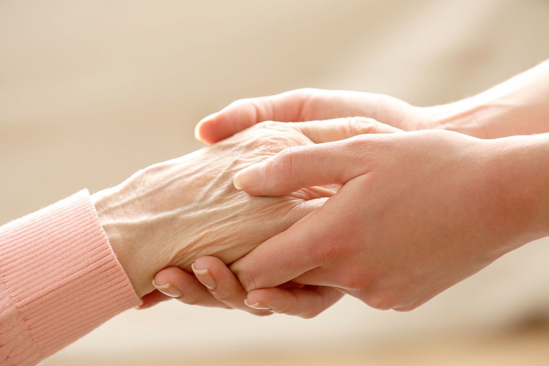 Two hands clasped together, one older, one younger, offering comfort.