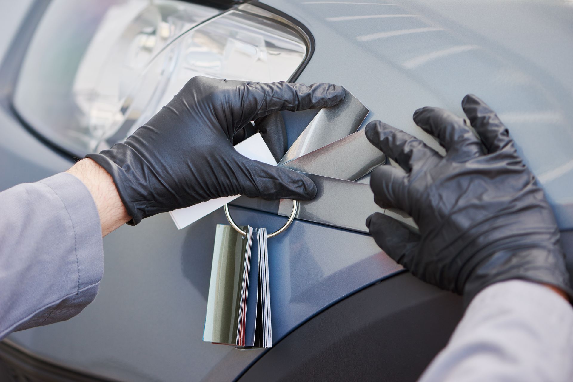 Gloved hands polishing a gray car door handle with a microfiber cloth