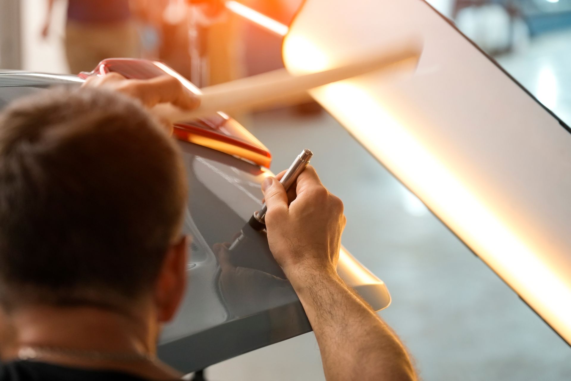 Person drawing on a large glass panel with a stylus in a brightly lit workspace