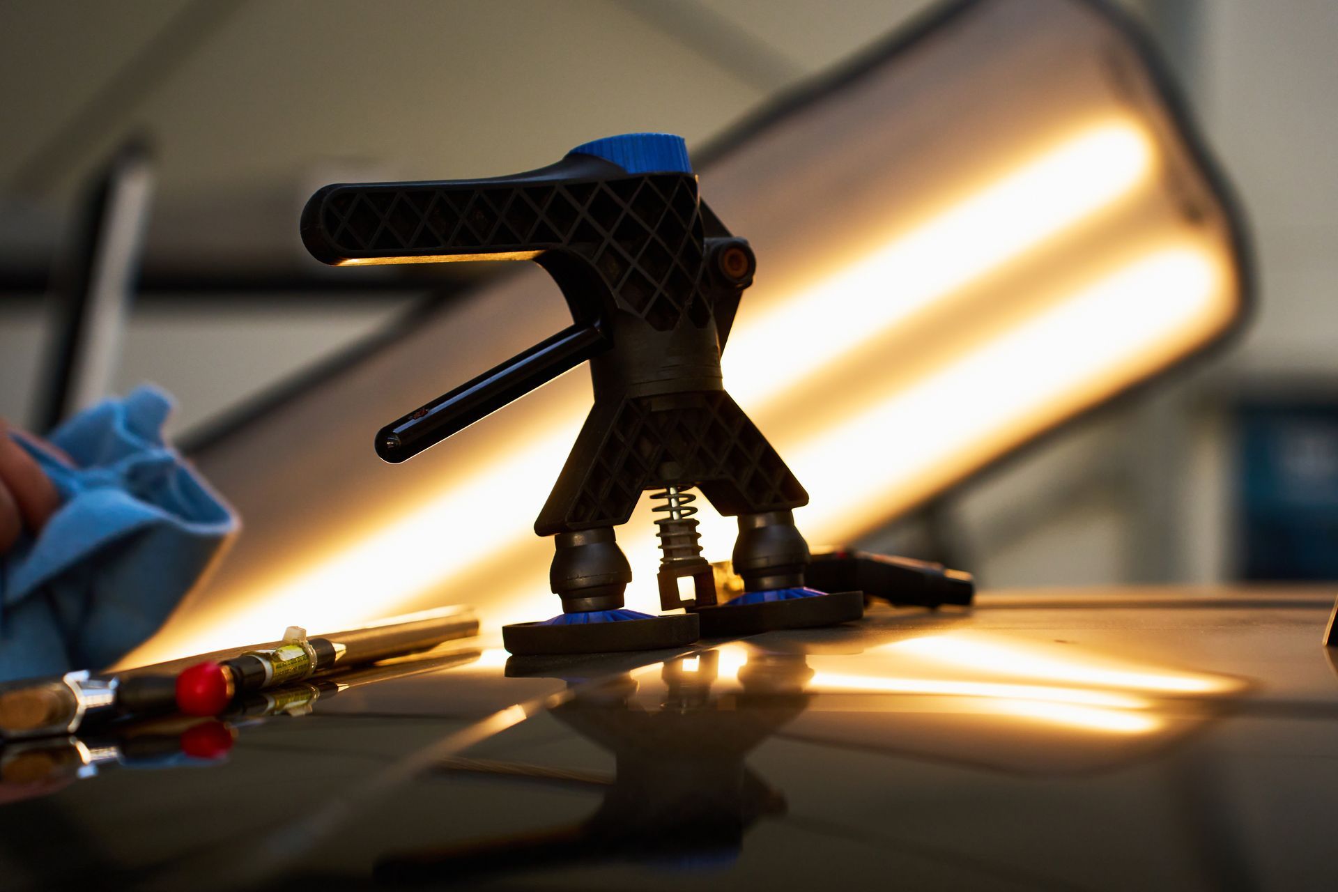 A small black robotic figure stands on a reflective surface with warm light glowing behind it.