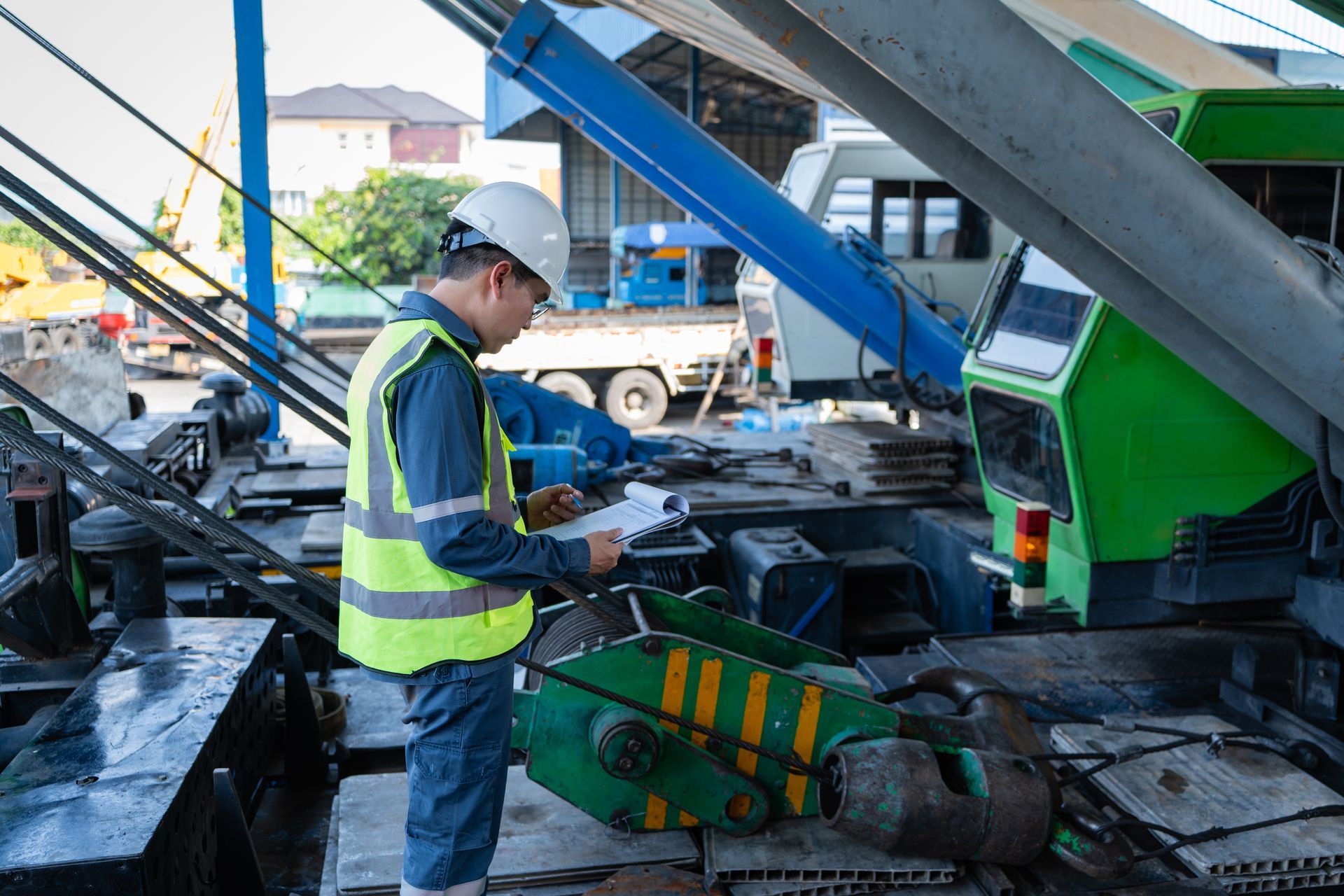 Worker in a hard hat and safety vest inspecting machinery at a construction site