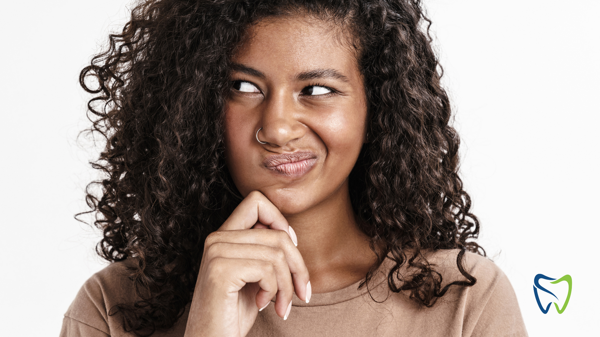 Woman with curly hair looking sideways and touching her chin against a white background