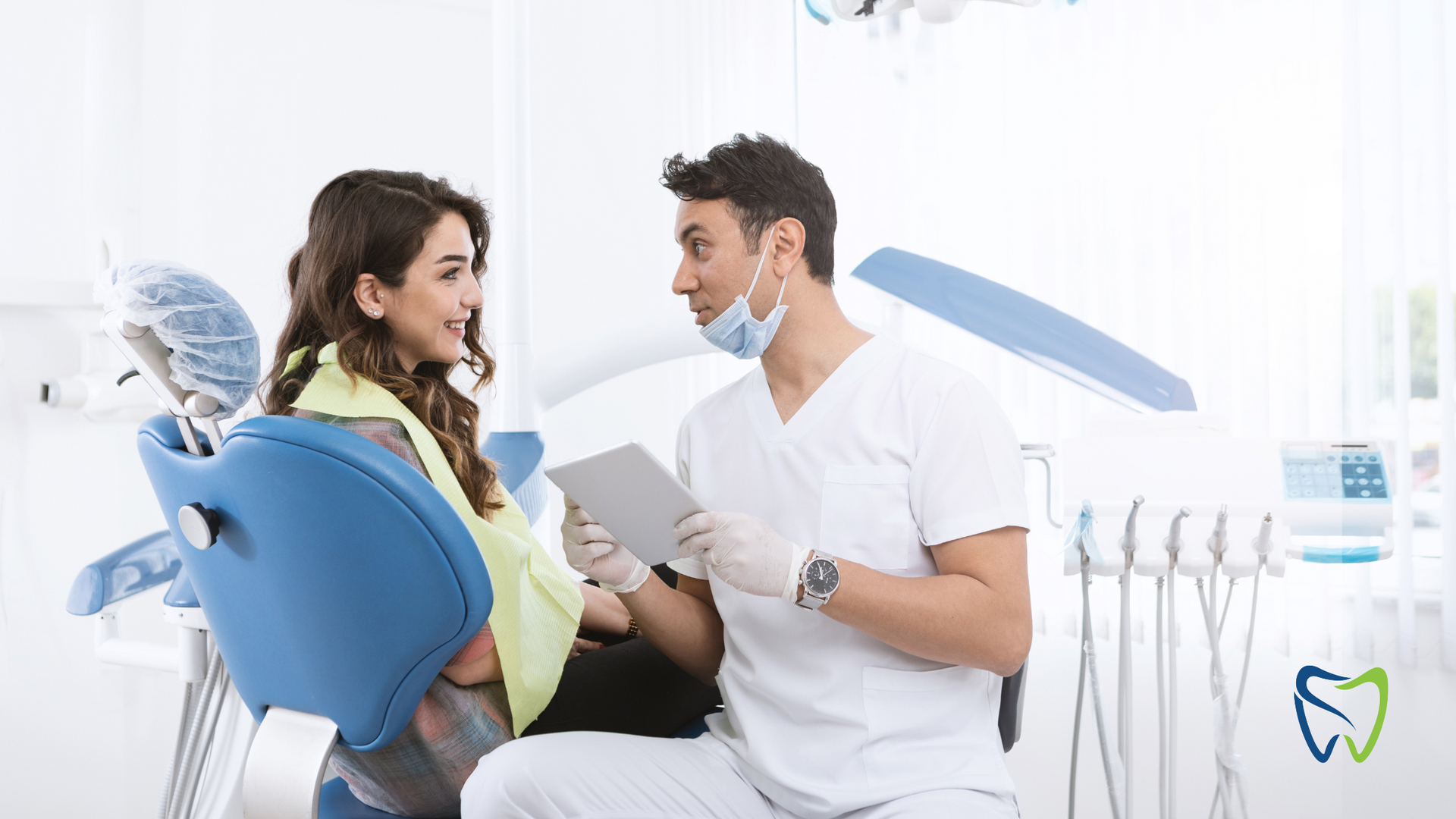 A dentist and patient in a bright dental office, reviewing information on a tablet.