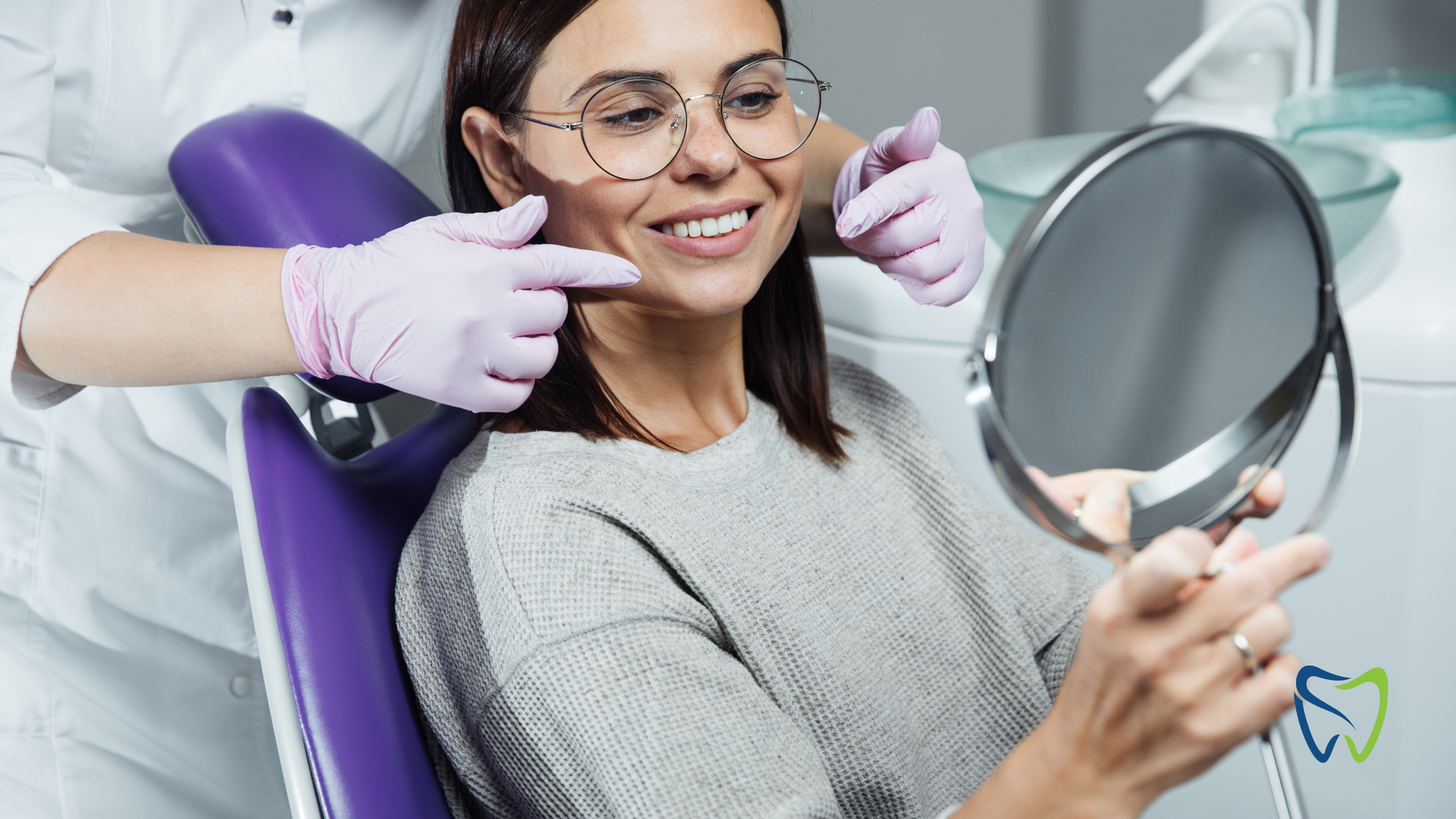 Woman smiling in a dental chair while holding a mirror during a dental exam
