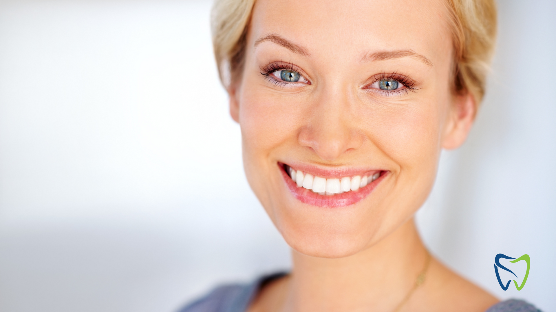 Smiling blond woman in a bright, close-up portrait against a soft gray background