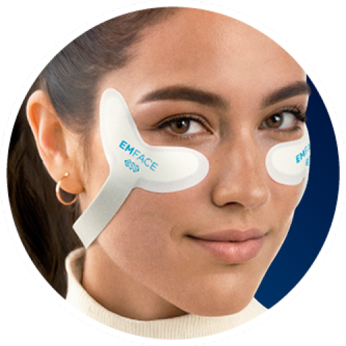 Woman wearing white under-eye patches labeled “EMFACE” against a blue background