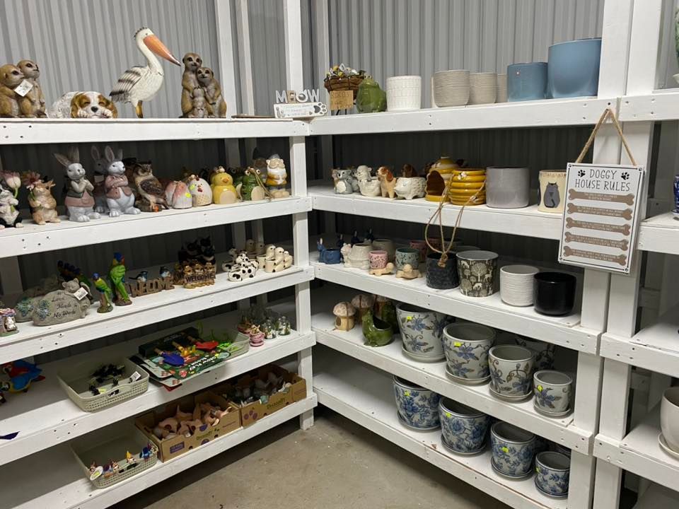 Shelves of ceramic mugs, bowls, and figurines in a small shop display, arranged neatly in a corner.