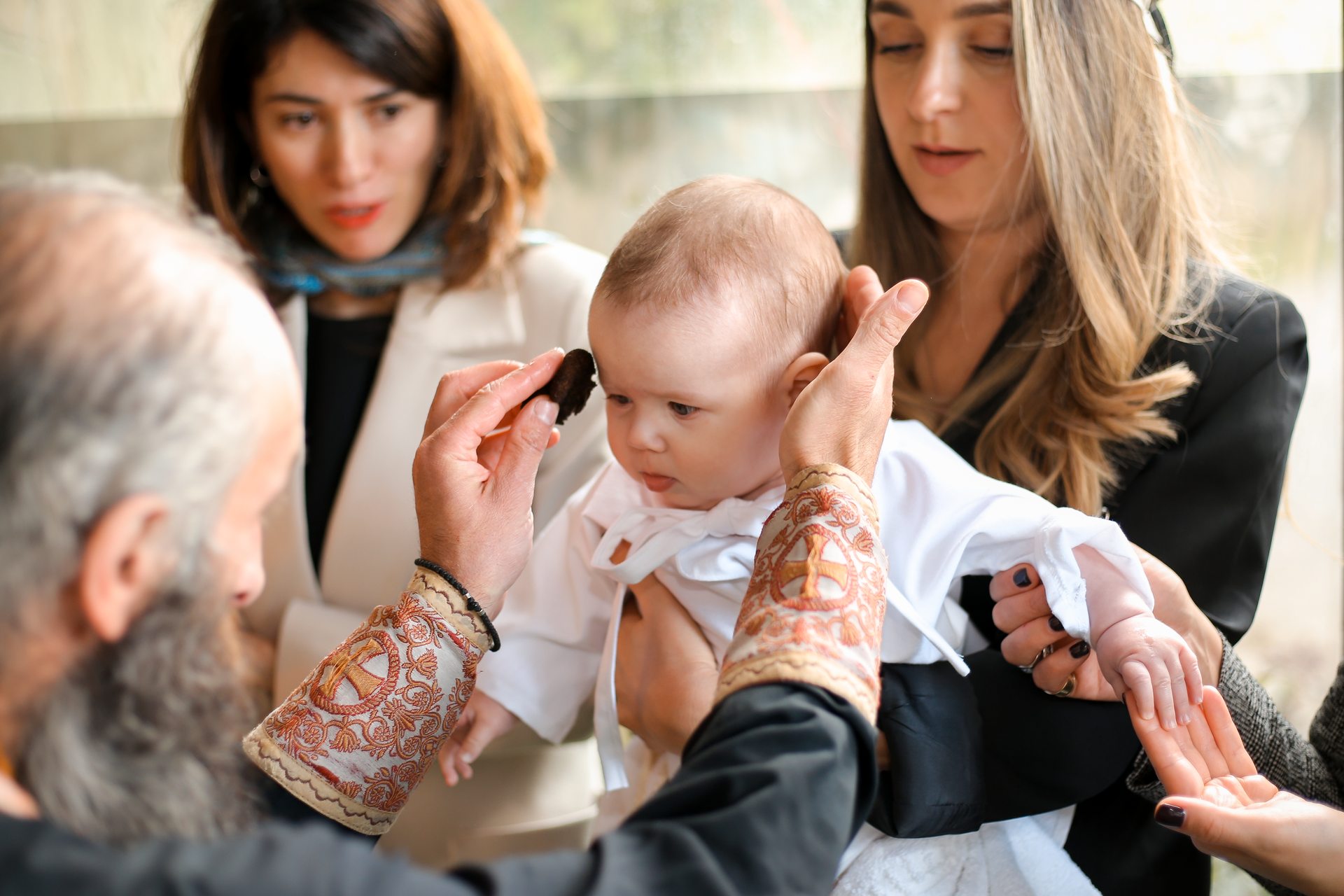 Baby being examined by a doctor while two adults watch closely in a bright clinic.