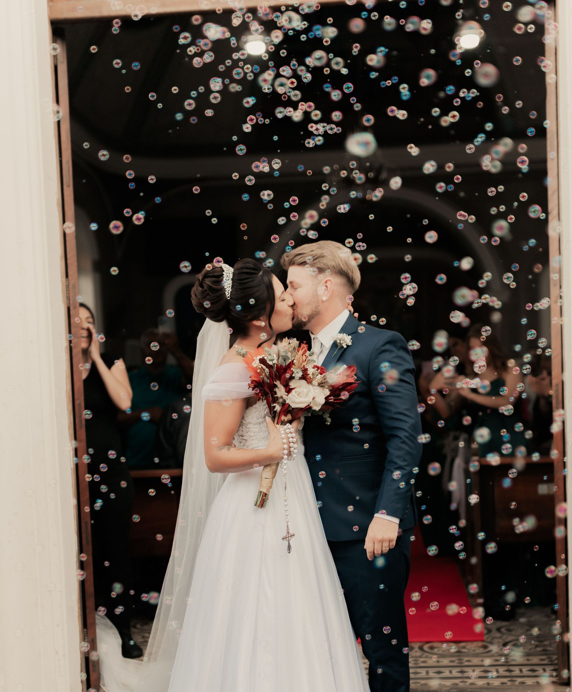 Wedding couple sharing a kiss under bubbles at a ceremony venue entrance