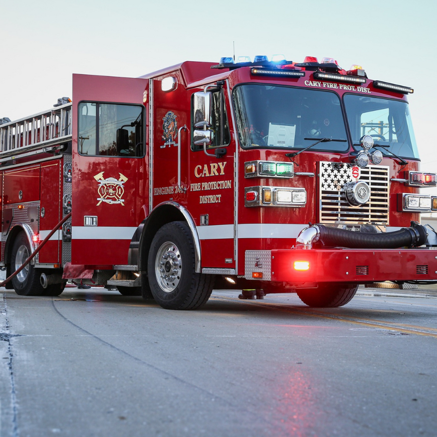 Red fire truck with flashing lights parked on a street at dusk