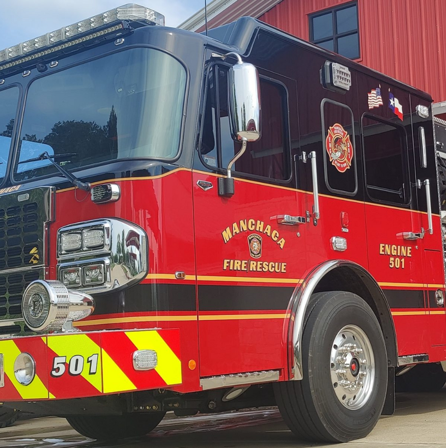 Red Manchester fire rescue engine 501 parked outside a building.