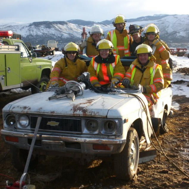 Rescue crew in yellow gear around a damaged car in a muddy, snowy area