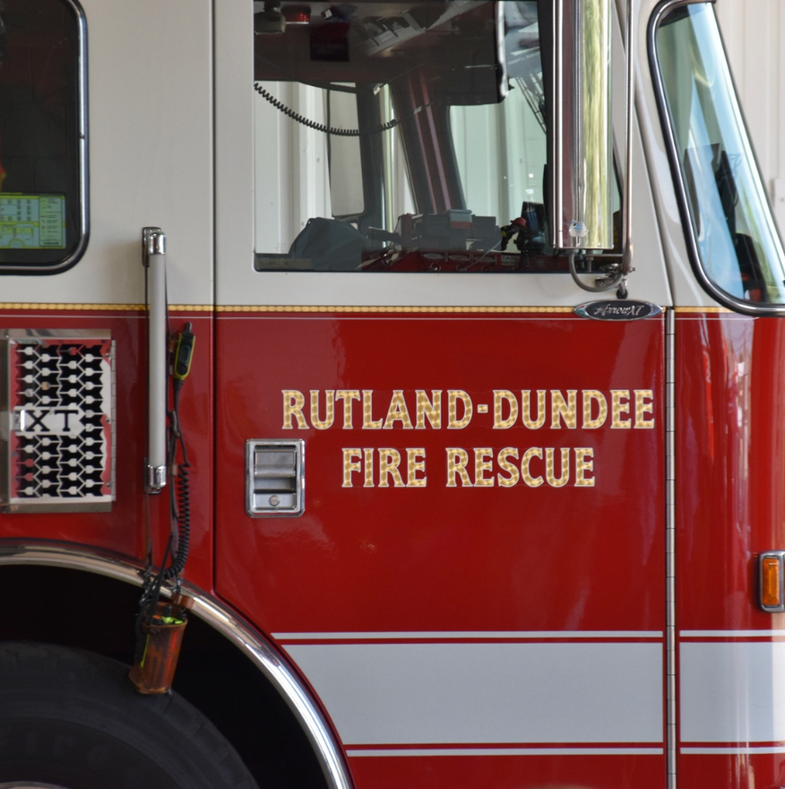 Rutland-Dundee Fire Rescue truck in red and white, side view of the cab and door logo.