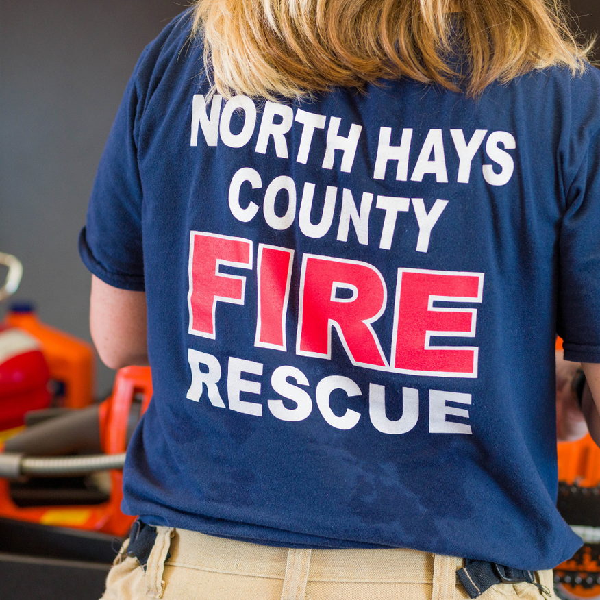 Back of navy shirt reading “North Hays County Fire Rescue” in white and red
