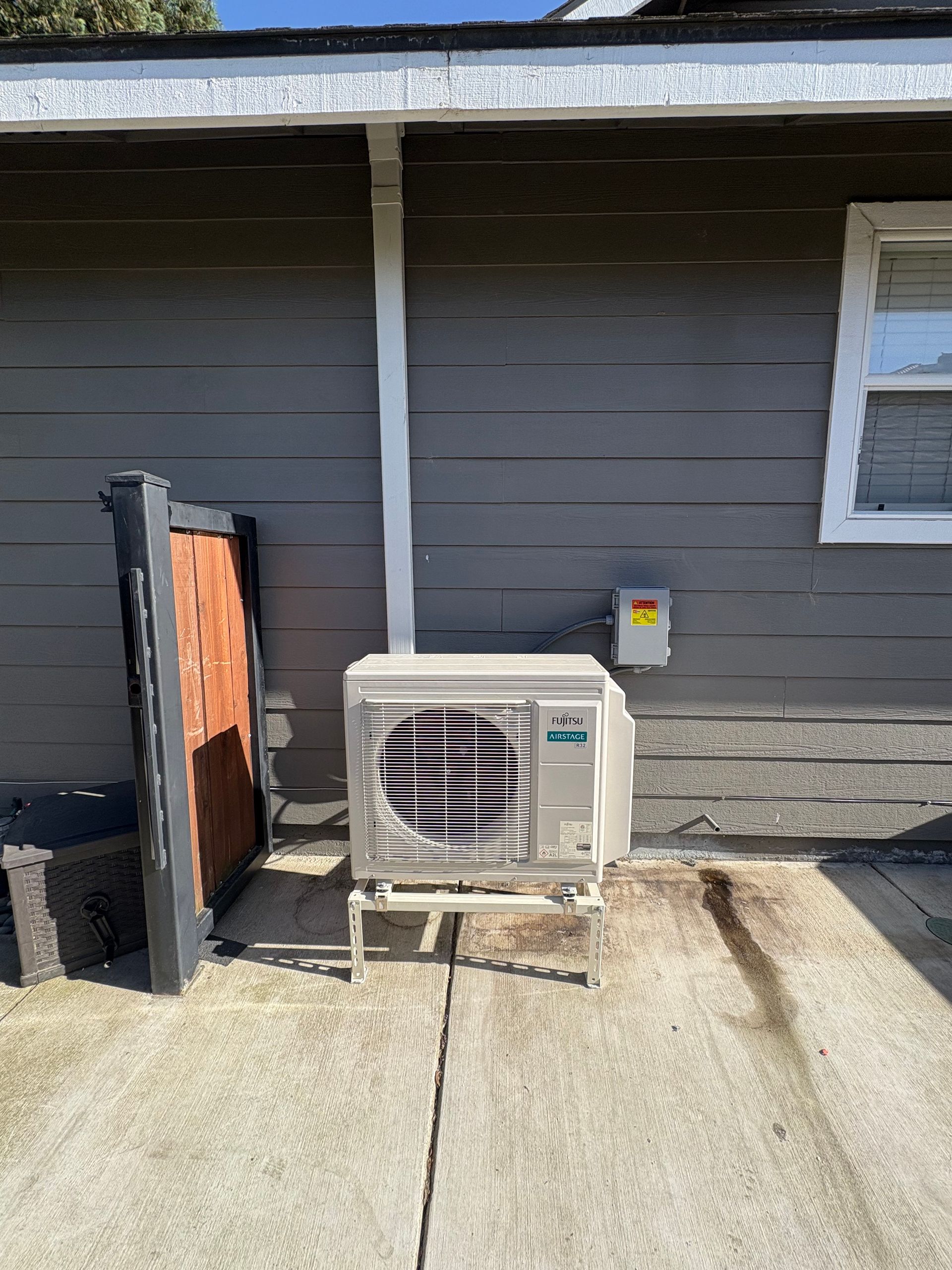 A large air conditioner is sitting on the side of a house.