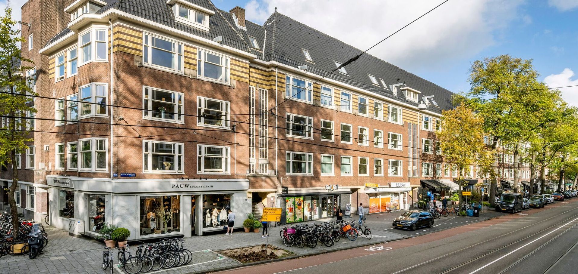 Een groot bakstenen gebouw met veel ramen staat op de hoek van een straat.