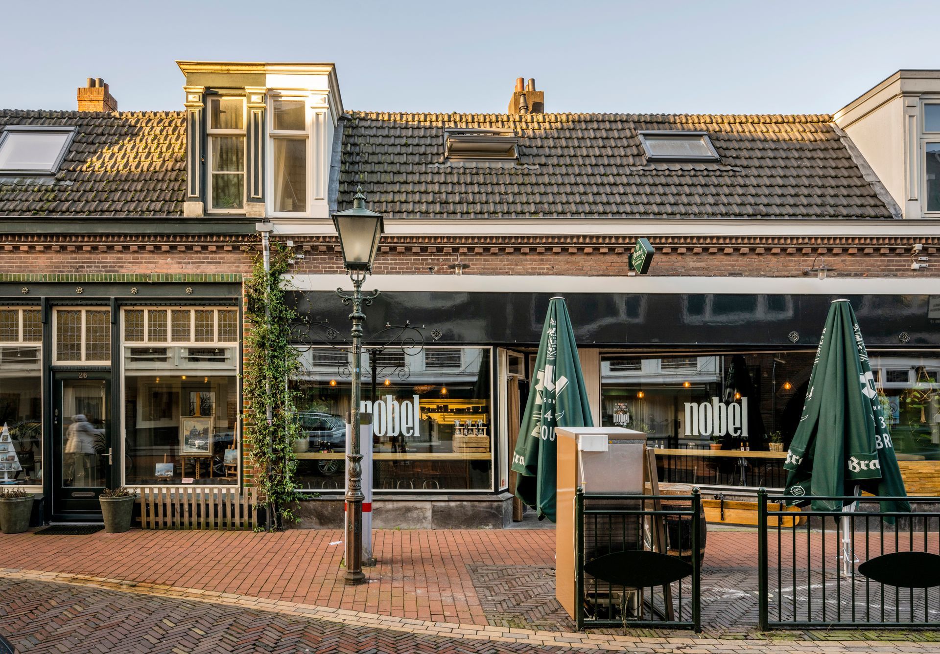 Een rij gebouwen met parasols en tafels ervoor.