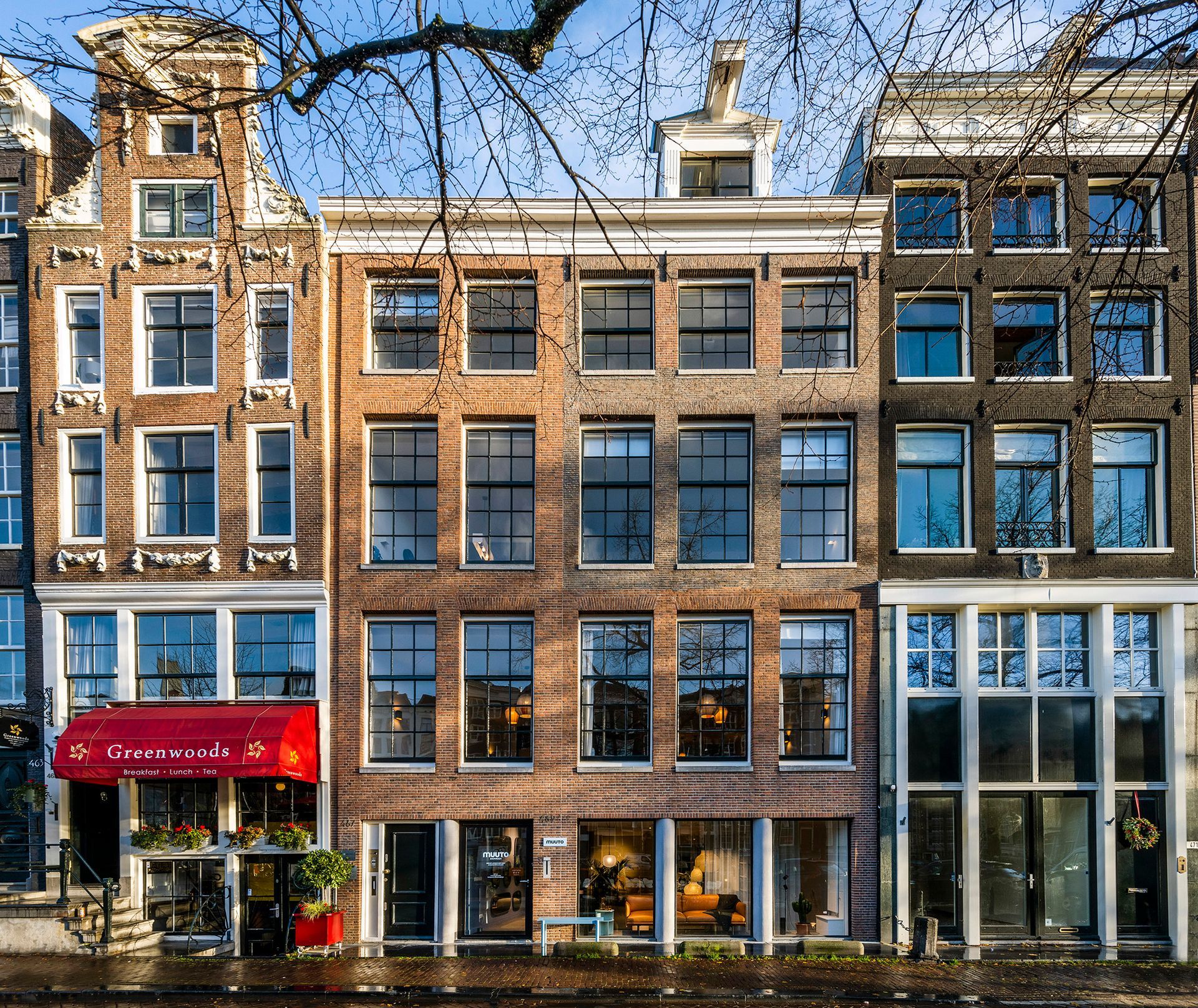 Een rij bakstenen gebouwen met een rode luifel waarop 'a' staat