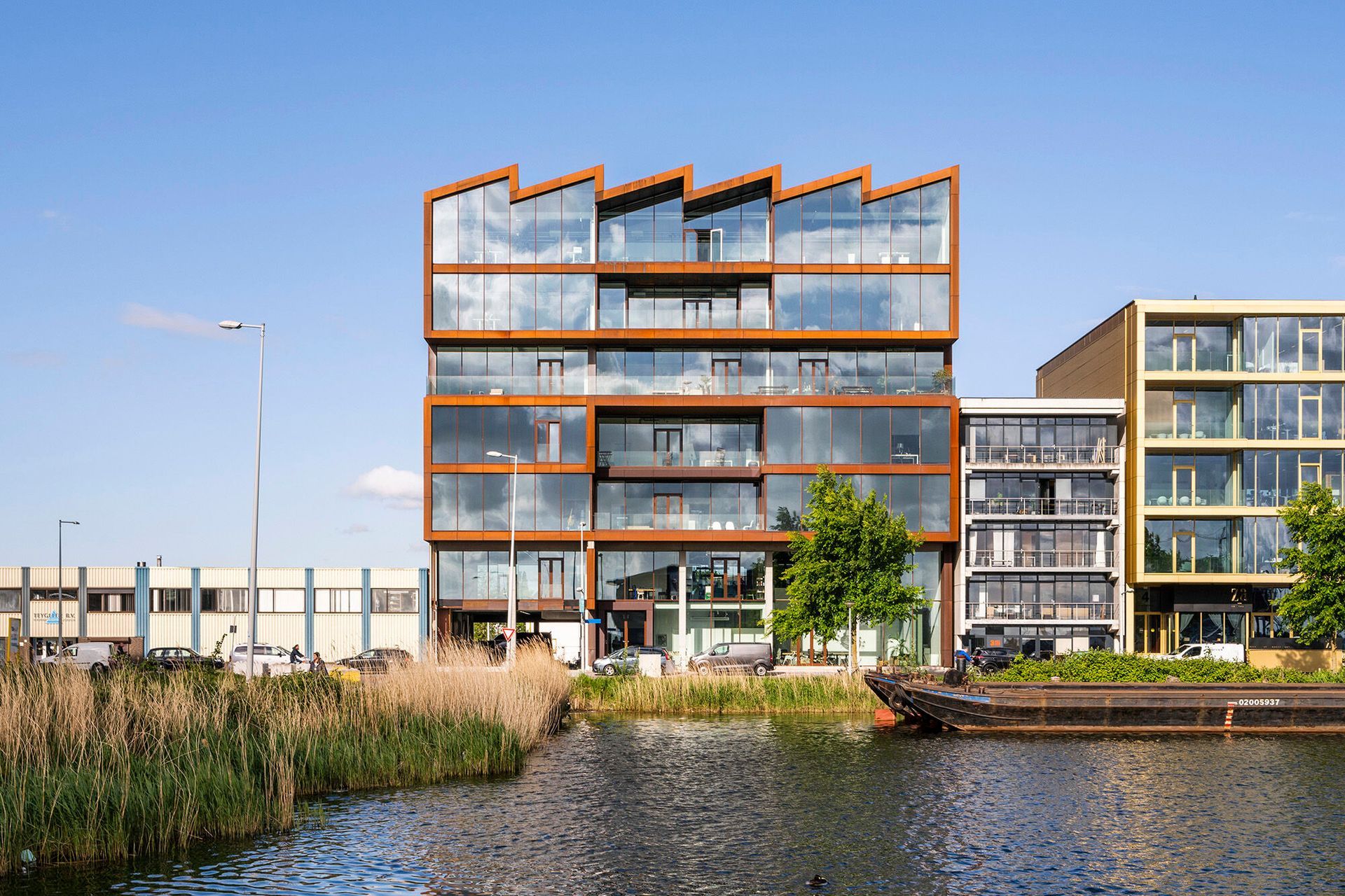 Een groot gebouw met veel ramen staat naast een waterpartij.