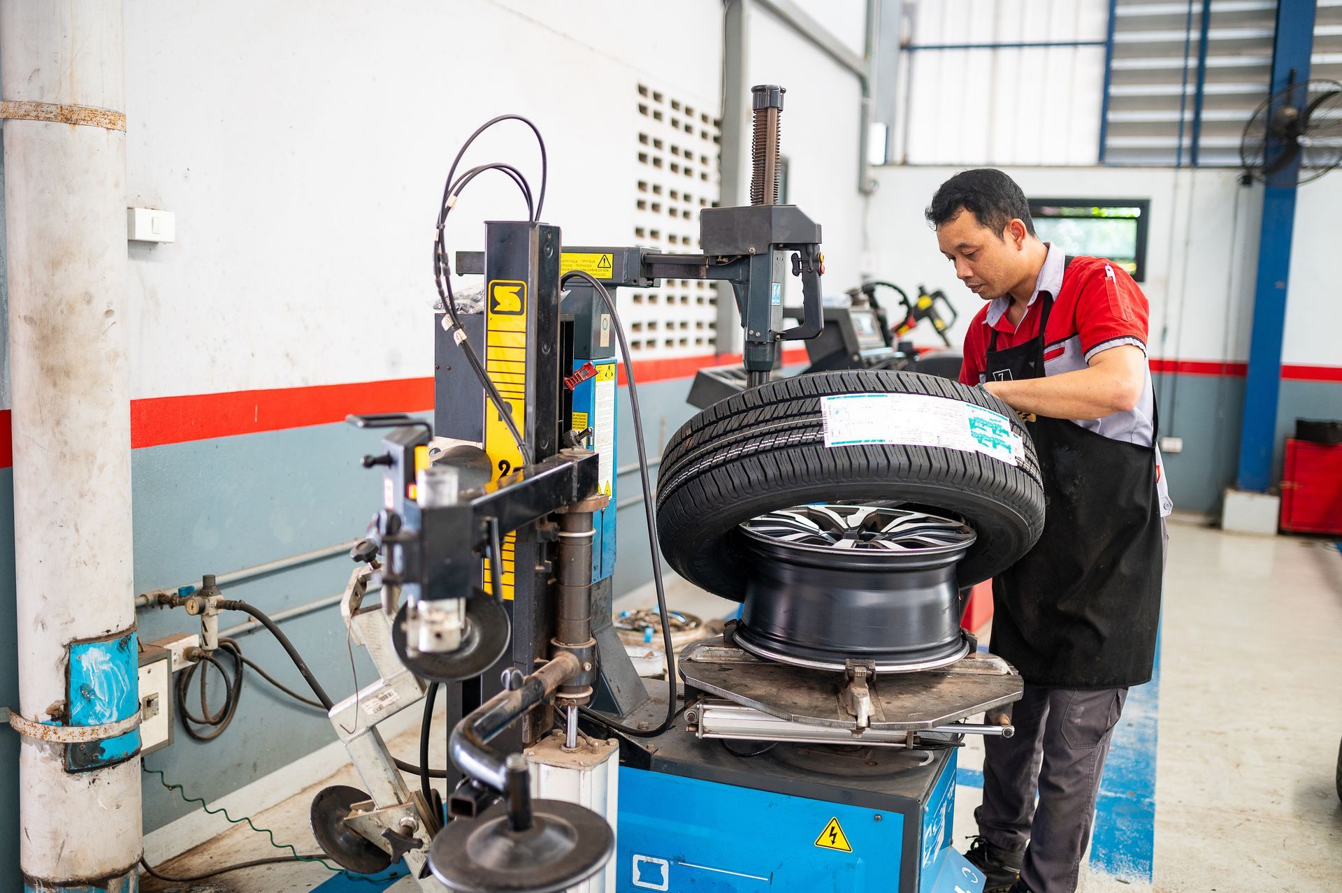 Mechanic inflating a tire on a tire-changing machine in an auto shop