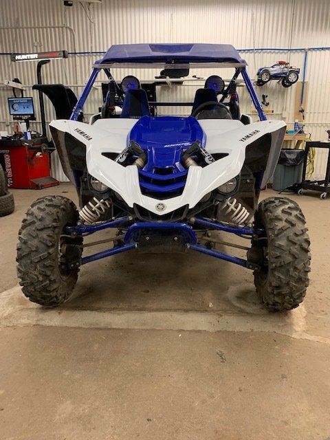 Blue and white off-road UTV with large tires parked in a garage