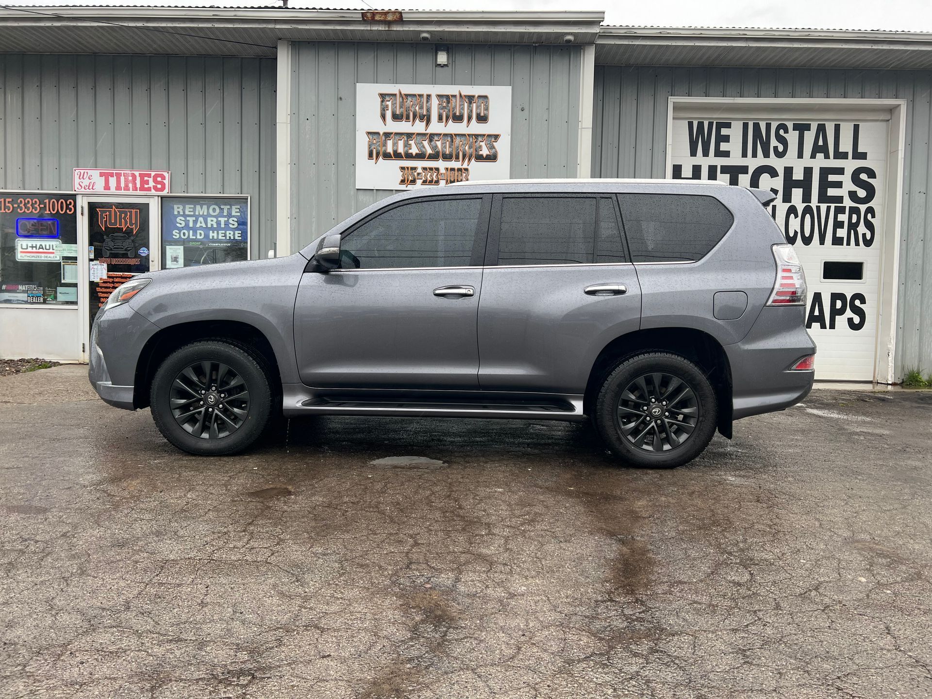 Gray SUV parked outside a storefront with protest signs in the background.