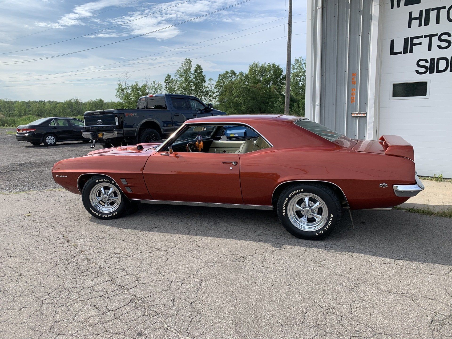 Red classic muscle car parked outside a building on a sunny day