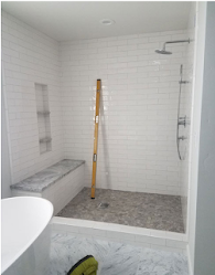 A bathroom with a walk in shower and a wooden level on the floor.