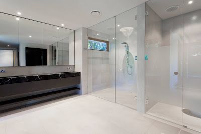 A bathroom with a walk in shower and two sinks.
