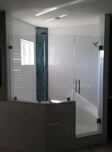 A bathroom with a walk in shower with a glass door