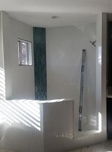 A bathroom with a walk in shower and a ladder