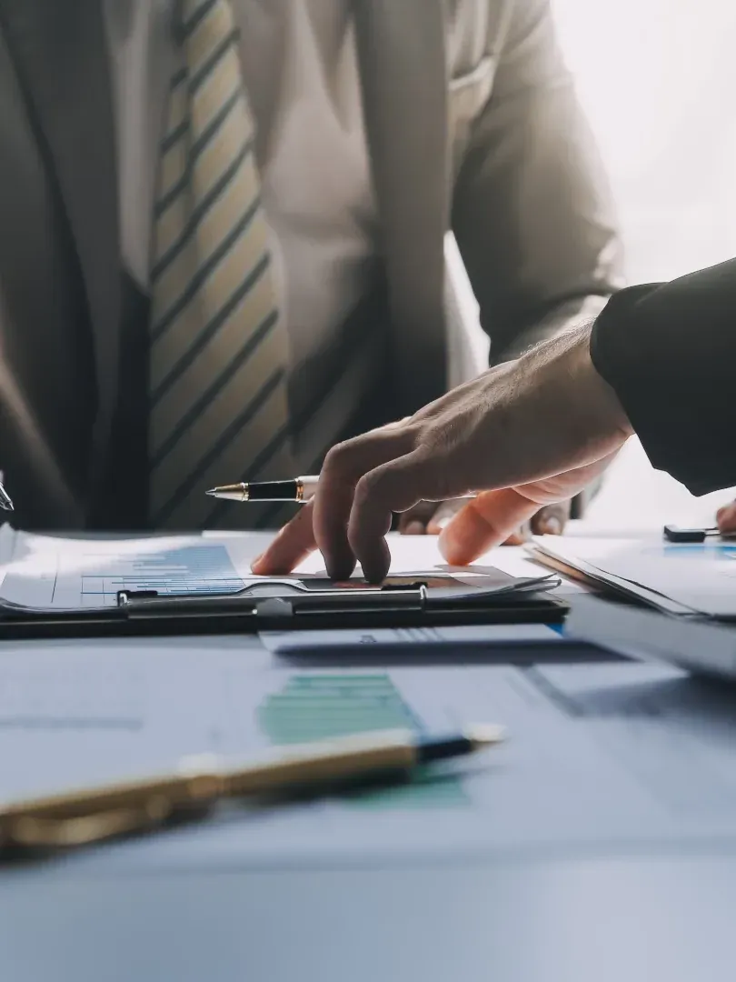 Hands pointing at documents and a calculator on a desk in a business meeting